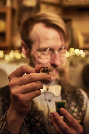 Ein steampunkig gekleideter Mann hält eine Besonderheit nach vorne.
