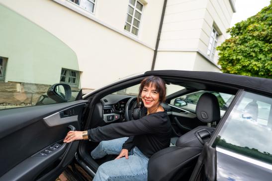 Social Media - Claudia Wolf, steigt freundlich aus dem Auto aus