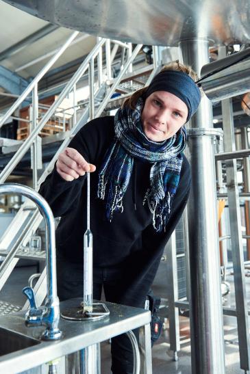 Brauerin zeigt ein Messwerkzeug